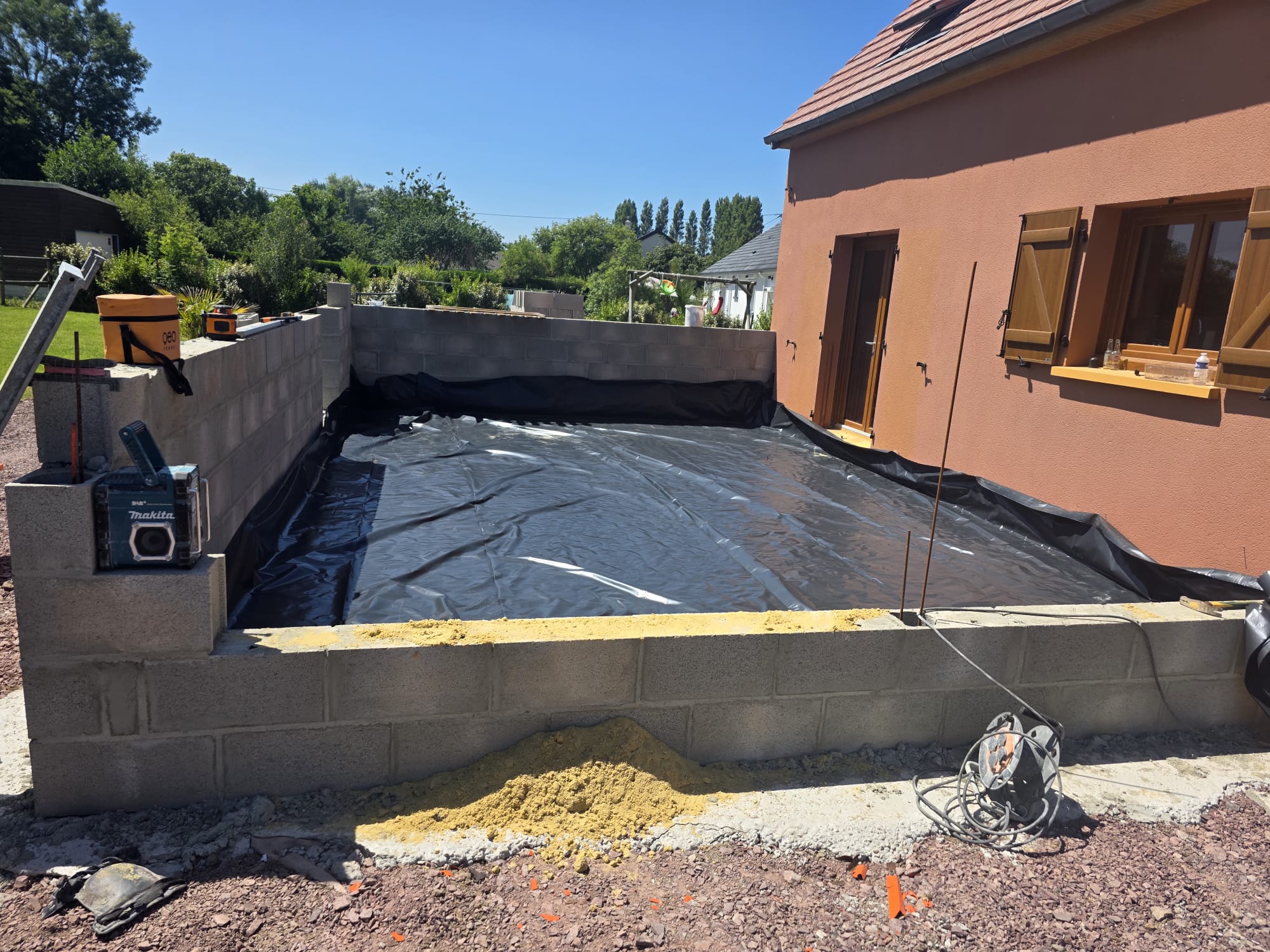 Construction d'une extension en blocs de béton avec bâche noire - LR Rénovation