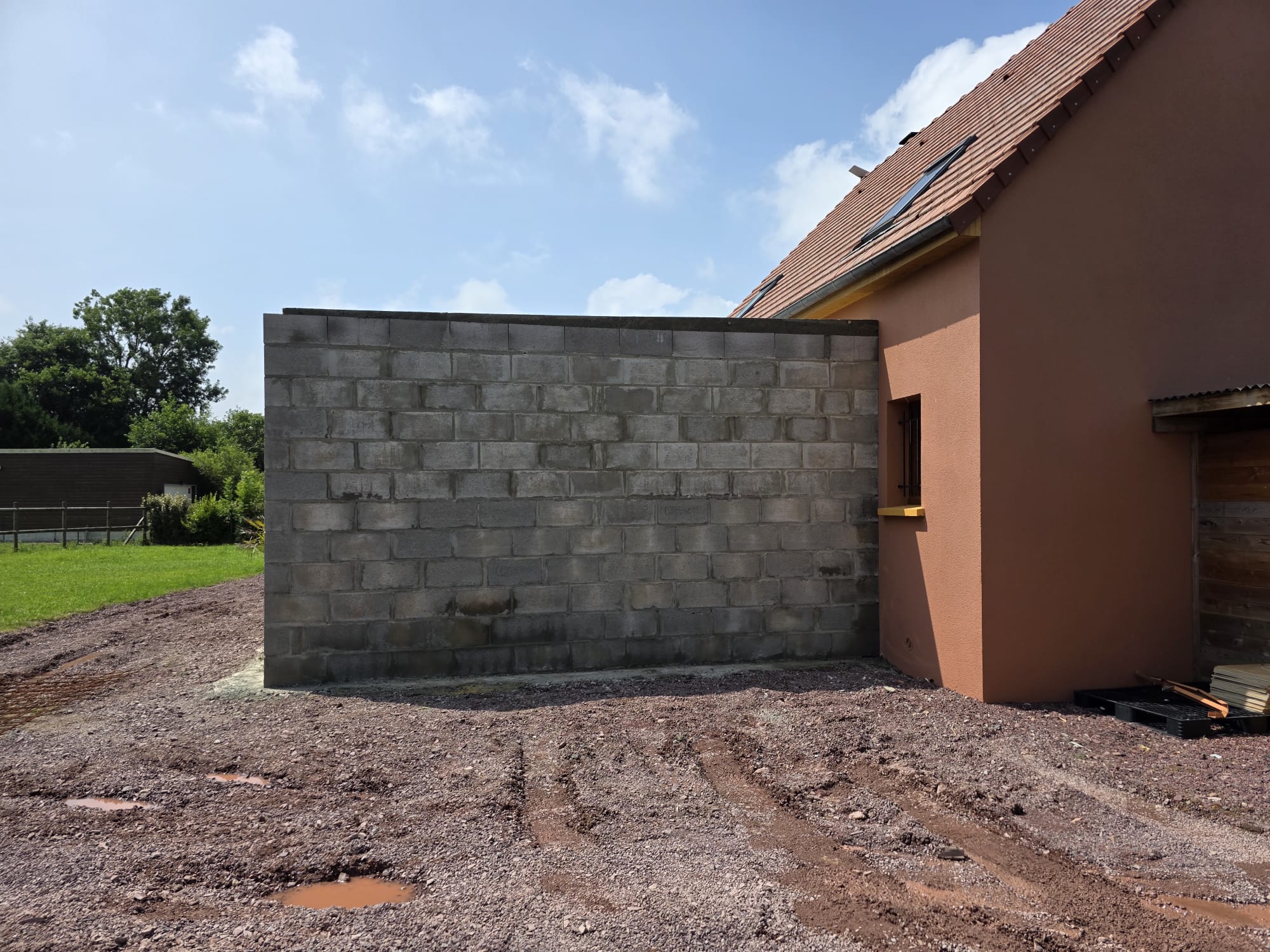 Extension en parpaings accolée à une maison avec façade rose et tuiles - LR Rénovation