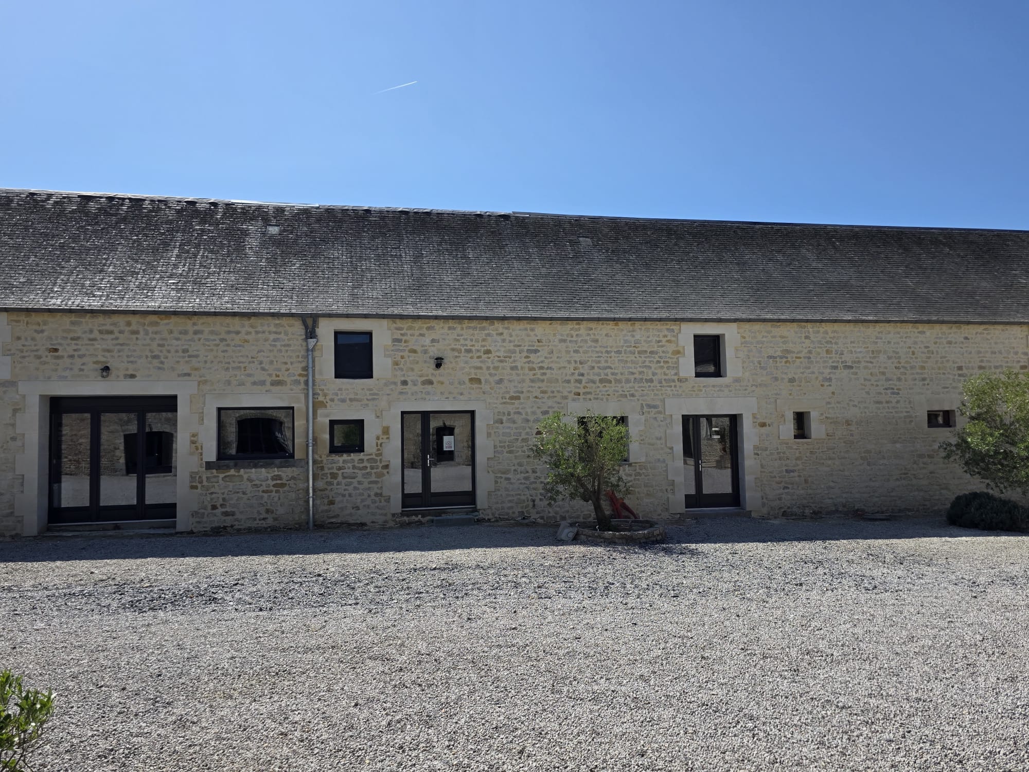 Façade en pierre rénovée avec fenêtres et portes vitrées noires - LR Rénovation Lison