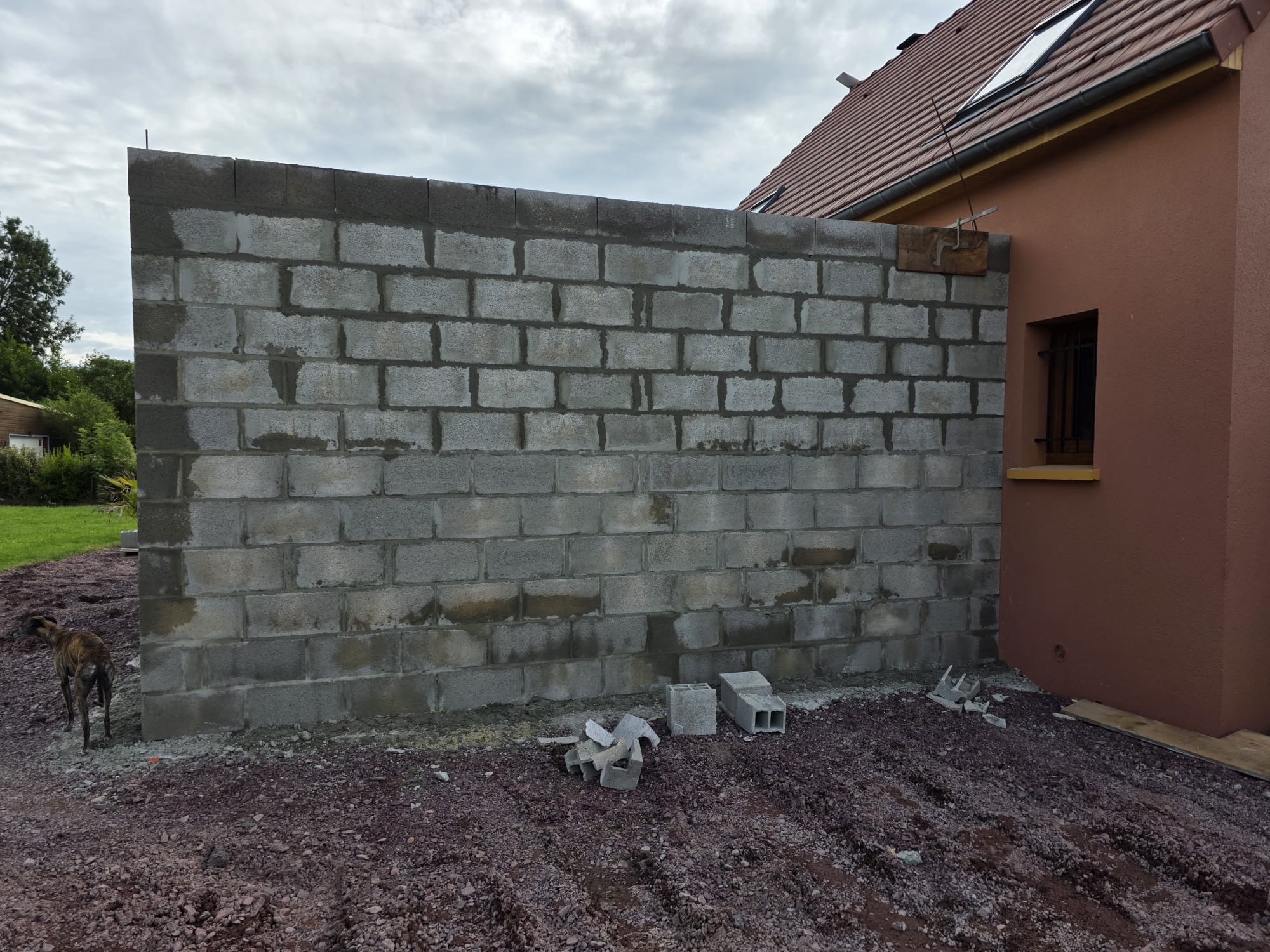 Mur en parpaings en construction contre une maison - LR Rénovation