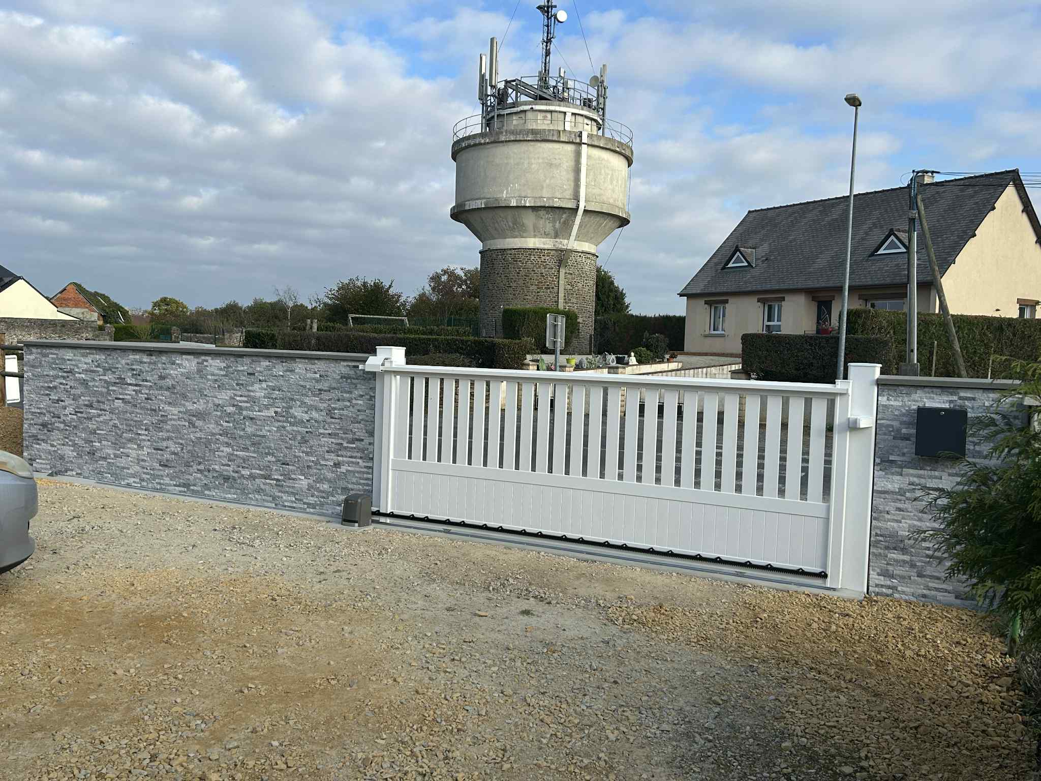 Portail blanc coulissant sur muret en pierres décoratives grises - pose de clôtures et portails par LR Renovation
