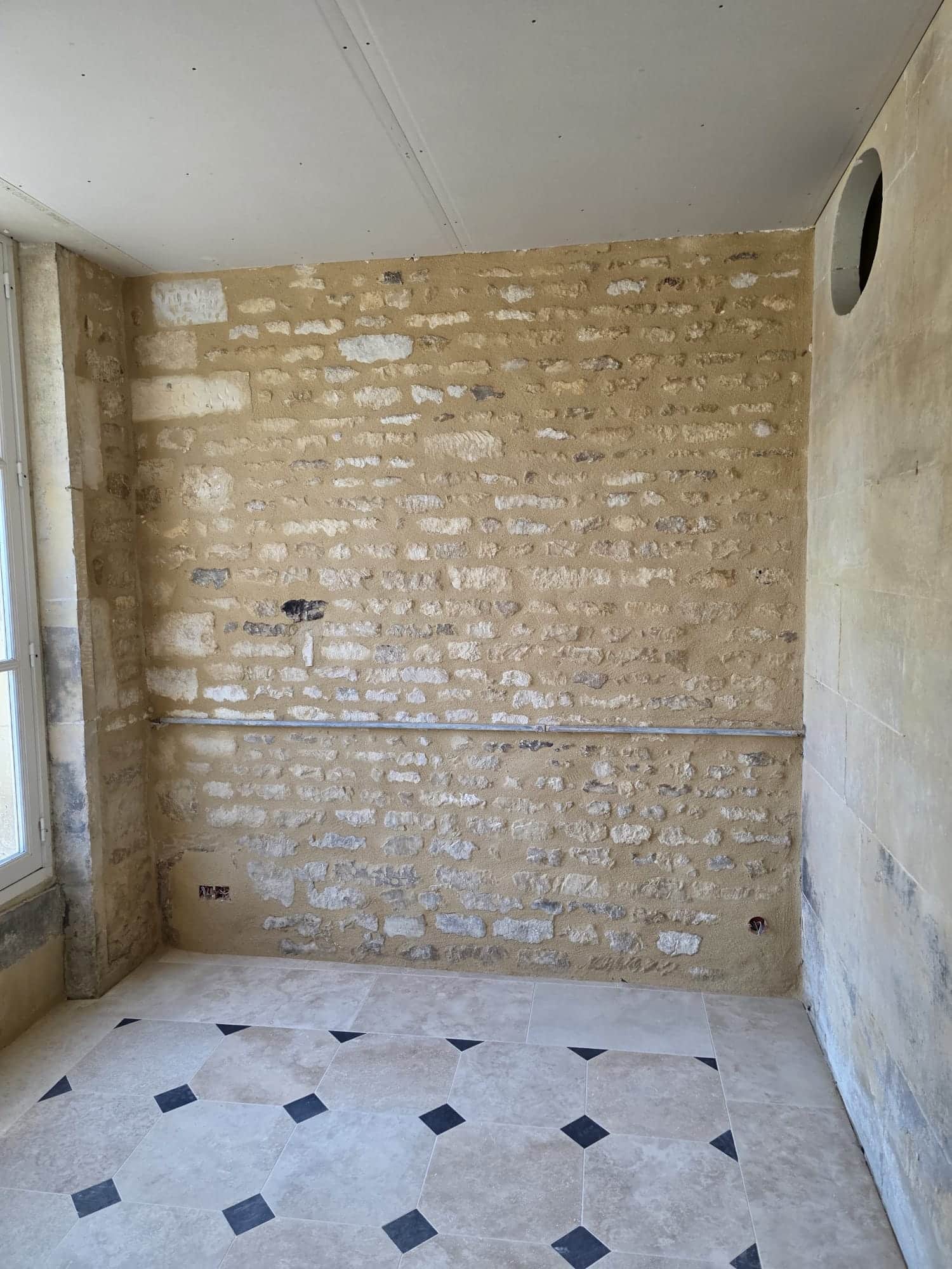 Pièce en rénovation avec mur en pierre apparente rénovée et carrelage neuf - LR Rénovation