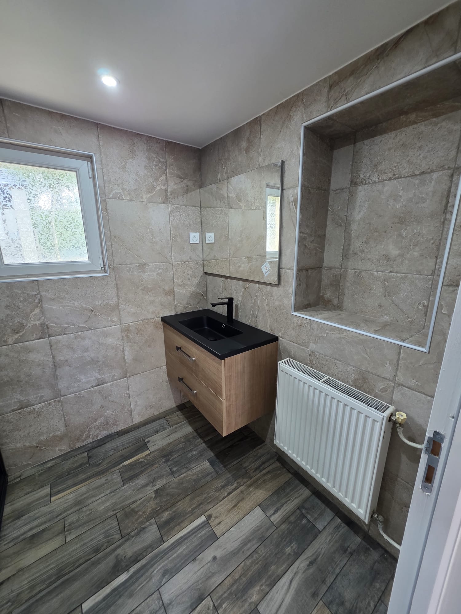 Salle de bain rénovée avec carrelage mural beige et vasque suspendue - LR Rénovation